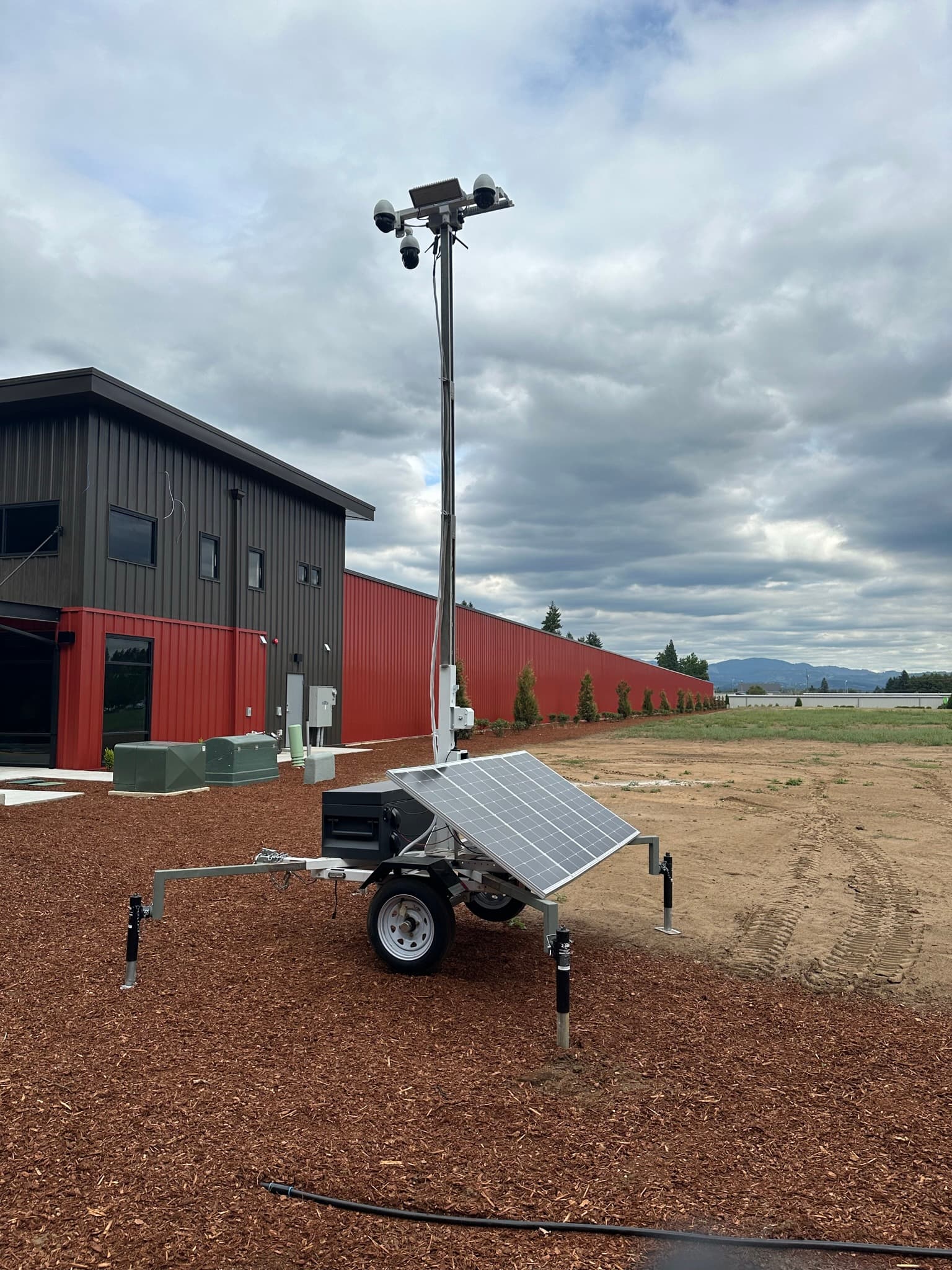 Solar-powered mobile surveillance trailer deployed beside a commercial facility