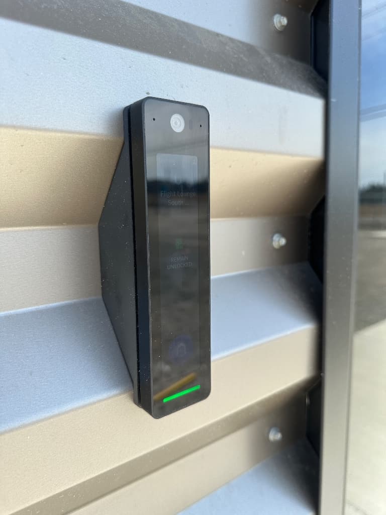 Black access-control reader installed on a metal commercial building