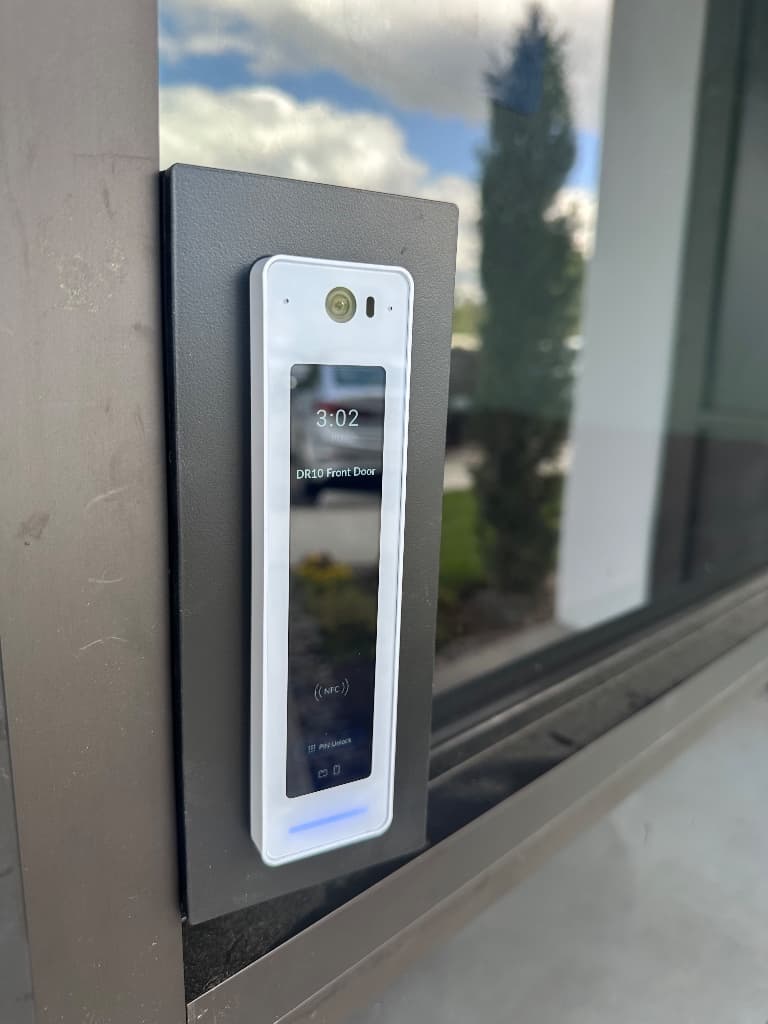 White access-control reader installed beside a commercial entry door